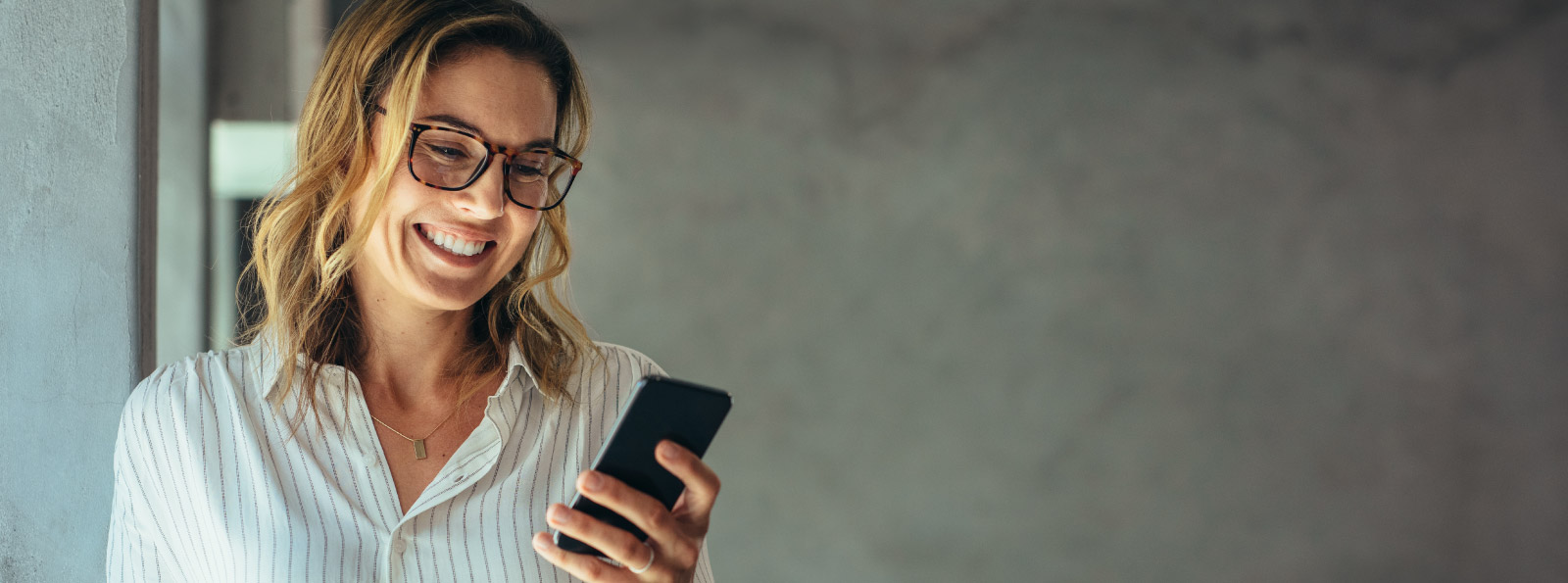 Woman smiling and looking at her phone.